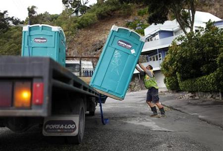 A man places portable toilets in a beach-side suburb of Christchurch that remains without running water after Tuesday's earthquake