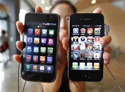 An employee of KT holds an Apple's iPhone 4 and a Samsung Electronics' Galaxy S in Seoul An employee of KT holds an Apple's iPhone 4 and a Samsung Electronics' Galaxy S in Seoul