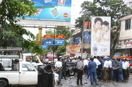 People stand near a damaged car after a blast in Mandalay People stand near a damaged car after a blast in Mandalay