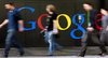 People walk past a logo next to the main entrance of the Google building in Zurich