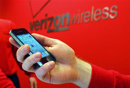 Employee holds out an iPhone for a customer at a Verizon store in Boston Employee holds out an iPhone for a customer at a Verizon store in Boston