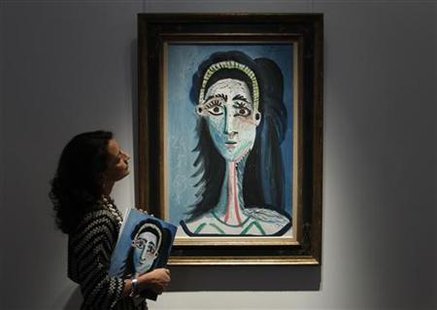 An employee poses for photographers in front of Pablo Picasso's ''Tete de femme'' painting at Christie's auction house in London