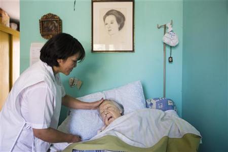 An elderly woman who is terminally ill receives attention in a room at the senile dementia building at the Canevaro old people's home in Lim An elderly woman who is terminally ill receives attention in a room at the senile dementia building at the Canevaro old people's home in Lim