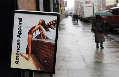 Pedestrians walk past an American Apparel sign outside one of their stores in New York Pedestrians walk past an American Apparel sign outside one of their stores in New York
