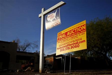 A realtor and bank-owned sign is displayed near a house for sale in Phoenix A realtor and bank-owned sign is displayed near a house for sale in Phoenix