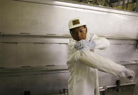 A worker fastens a plastic cover over a Kevlar sleeve made to protect his arms as he returns from a break at the West Liberty Food processin A worker fastens a plastic cover over a Kevlar sleeve made to protect his arms as he returns from a break at the West Liberty Food processin