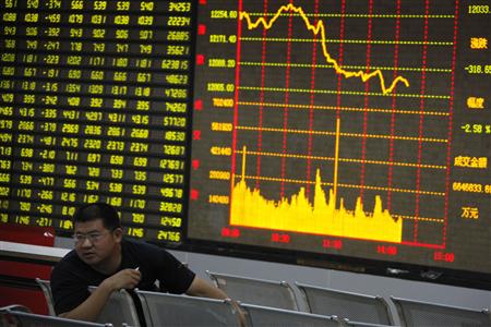 A man sits in front of an electronic board showing stock information at a brokerage house in Huaibei A man sits in front of an electronic board showing stock information at a brokerage house in Huaibei