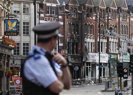 A police officers stands near a burnt out shop in Clapham Junction, in south London A police officers stands near a burnt out shop in Clapham Junction, in south London