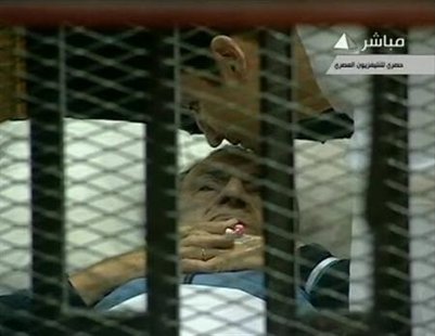 Former Egyptian President Hosni Mubarak (L) is kissed on the forehead by his son Alaa in the courtroom during his trial at the police academ
