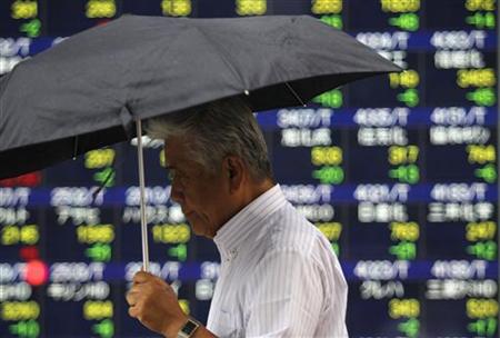 A man walks past an electronic board displaying share prices in Tokyo A man walks past an electronic board displaying share prices in Tokyo