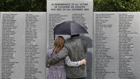 A couple shelters from the rain under an umbrella as they look at the main headstone in the Lockerbie air disaster memorial garden in Locker A couple shelters from the rain under an umbrella as they look at the main headstone in the Lockerbie air disaster memorial garden in Locker