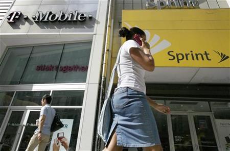 A woman talks on her phone as she walks past T-mobile and Sprint wireless stores in New York A woman talks on her phone as she walks past T-mobile and Sprint wireless stores in New York