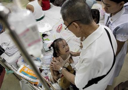 A child cries as she is comforted by a relative inside a crowded ward filled with dengue patients at a hospital in Quezon City, metro Manila