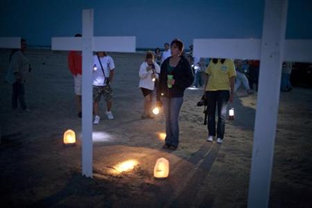 Participants gather around crosses honoring the workers who died on the Deepwater Horizon oil platform, during a service marking the one-yea Participants gather around crosses honoring the workers who died on the Deepwater Horizon oil platform, during a service marking the one-yea