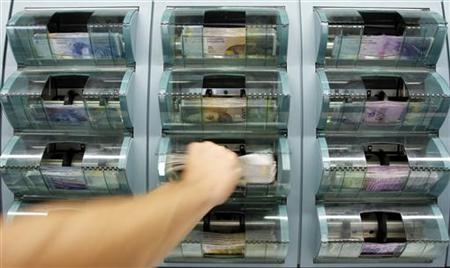 A bank clerk removes 200 Swiss franc banknotes out of a money counter in a bank in Zurich A bank clerk removes 200 Swiss franc banknotes out of a money counter in a bank in Zurich
