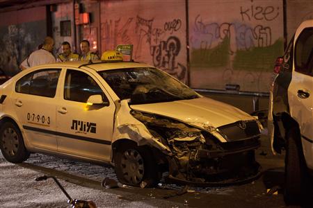 Israeli policemen inspect the scene of a commandeered taxi cab in Tel Aviv