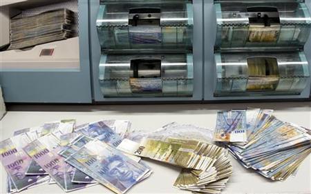 Swiss franc banknotes of several values are sorted in a money counter in a bank in Zurich Swiss franc banknotes of several values are sorted in a money counter in a bank in Zurich