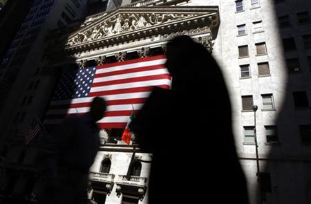 The sun lights the exterior of the New York Stock Exchange, as people walk past on the shadowed street The sun lights the exterior of the New York Stock Exchange, as people walk past on the shadowed street