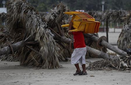 A resident carries plastic chairs to a safe place at a beach in Tuxpan A resident carries plastic chairs to a safe place at a beach in Tuxpan