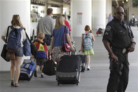 Travelers walk past a police officer at Los Angeles International Airport Travelers walk past a police officer at Los Angeles International Airport