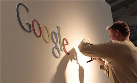 Man works on Google logo at exhibition stand at CeBIT computer fair in Hanover Man works on Google logo at exhibition stand at CeBIT computer fair in Hanover
