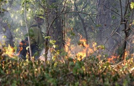 A U.S. forestry worker watches a controlled burn created to seal off a wildfire's path as it approaches a house near Bastrop, Texas A U.S. forestry worker watches a controlled burn created to seal off a wildfire's path as it approaches a house near Bastrop, Texas