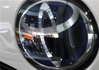 People are reflected on a Toyota Motor vehicle logo at the company showroom in Tokyo