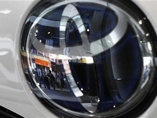 People are reflected on a Toyota Motor vehicle logo at the company showroom in Tokyo