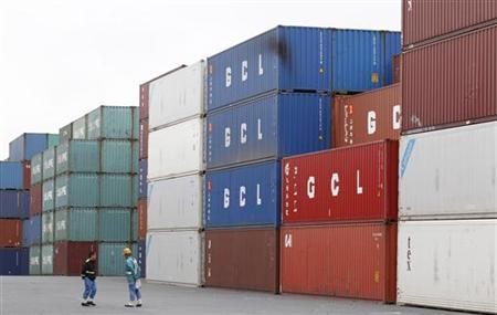 Workers stand in front of container at an industrial port in Tokyo Workers stand in front of container at an industrial port in Tokyo