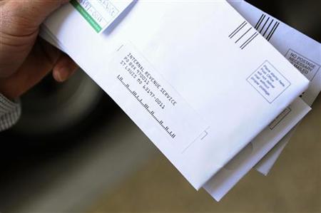 A man holds his envelopes as he waits in line to mail his family's income tax returns at a mobile post office near the Internal Revenue Serv A man holds his envelopes as he waits in line to mail his family's income tax returns at a mobile post office near the Internal Revenue Serv