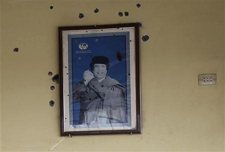 A bullet-riddled picture of Muammar Gaddafi hangs on the wall of a cafetaria at a gas station of Bou Hadi town A bullet-riddled picture of Muammar Gaddafi hangs on the wall of a cafetaria at a gas station of Bou Hadi town