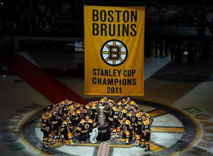 Boston Bruins players pose with the Stanley Cup trophy and their championship banner before taking on the Philadelphia Flyers in the NHL sea Boston Bruins players pose with the Stanley Cup trophy and their championship banner before taking on the Philadelphia Flyers in the NHL sea