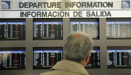A traveler checks a flight information board at Newark Liberty International Airport A traveler checks a flight information board at Newark Liberty International Airport