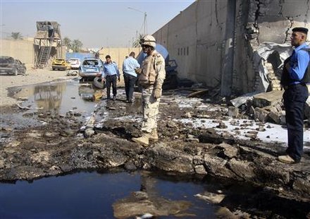 A soldier and Policemen inspect the site of a bomb attack at a police station in Baghdad's Hurriya district