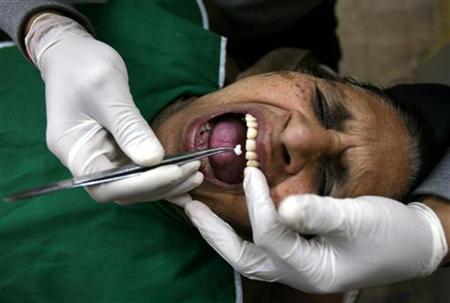 A dentist checks the teeth of a woman during a free treatment camp at a government dental hospital in Jammu A dentist checks the teeth of a woman during a free treatment camp at a government dental hospital in Jammu