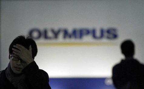 Men walk past a sign of Olympus Corp outside the company's showroom in Tokyo Men walk past a sign of Olympus Corp outside the company's showroom in Tokyo