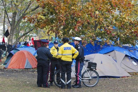 Police stand in front of the makeshift tent community at the the "Occupy Toronto" movement at St. James Park in Toronto Police stand in front of the makeshift tent community at the the "Occupy Toronto" movement at St. James Park in Toronto