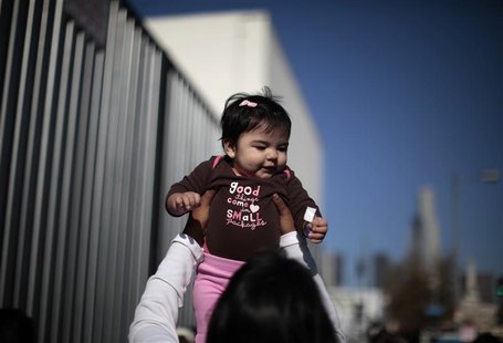 A woman plays with a baby as they wait to go into a "Back-to-School" giveaway at the Fred Jordan Mission in Los Angeles A woman plays with a baby as they wait to go into a "Back-to-School" giveaway at the Fred Jordan Mission in Los Angeles