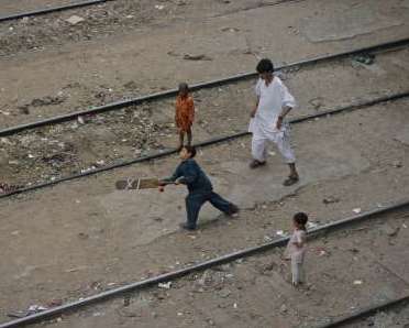 Boys play cricket along railway tracks in Karachi July 25, 2011. REUTERS/Athar Hussain