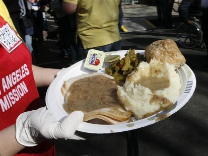 A volunteer carries one of thousands of early Thanksgiving meals served to homeless people in downtown Los Angeles A volunteer carries one of thousands of early Thanksgiving meals served to homeless people in downtown Los Angeles