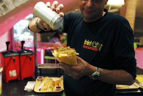 A cook sprinkles salt on fries at a cafe in the Frietmuseum in Bruges A cook sprinkles salt on fries at a cafe in the Frietmuseum in Bruges
