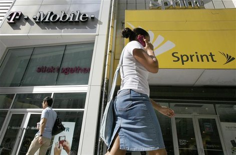 A woman talks on her phone as she walks past T-mobile and Sprint wireless stores in New York A woman talks on her phone as she walks past T-mobile and Sprint wireless stores in New York