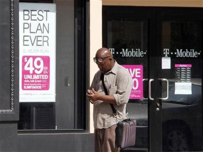 A man checks his mobile phone as he walks past a T-Mobile store in downtown Los Angeles A man checks his mobile phone as he walks past a T-Mobile store in downtown Los Angeles