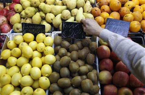 A fruit seller adjusts a price tag in a market in downtown Rome A fruit seller adjusts a price tag in a market in downtown Rome