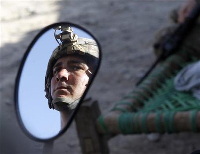 U.S. soldier is reflected in a mirror of a motorcycle during a patrol in a village near Combat Outpost Penich in Khas Konar district