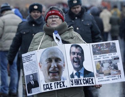 A woman carries a board displaying the portraits of Russia's President Medvedev and PM Putin during a sanctioned rally on a bridge near Bolo A woman carries a board displaying the portraits of Russia's President Medvedev and PM Putin during a sanctioned rally on a bridge near Bolo