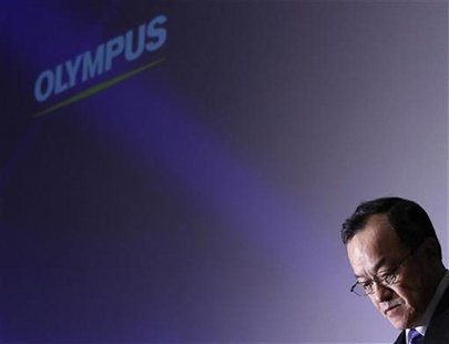 Olympus Corp's President Shuichi Takayama stands in front of its logo at the end of a news conference in Tokyo Olympus Corp's President Shuichi Takayama stands in front of its logo at the end of a news conference in Tokyo