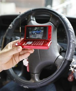 A woman watches television through her mobile phone in the car during a photocall in Tokyo A woman watches television through her mobile phone in the car during a photocall in Tokyo