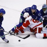 Detroit Red Wings' Holmstrom fights for the puck against Vancouver Canucks' Edler in front of Canucks goaltender Luongo during the third per