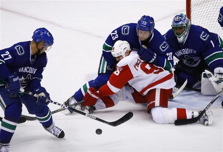 Detroit Red Wings' Holmstrom fights for the puck against Vancouver Canucks' Edler in front of Canucks goaltender Luongo during the third per Detroit Red Wings' Holmstrom fights for the puck against Vancouver Canucks' Edler in front of Canucks goaltender Luongo during the third per